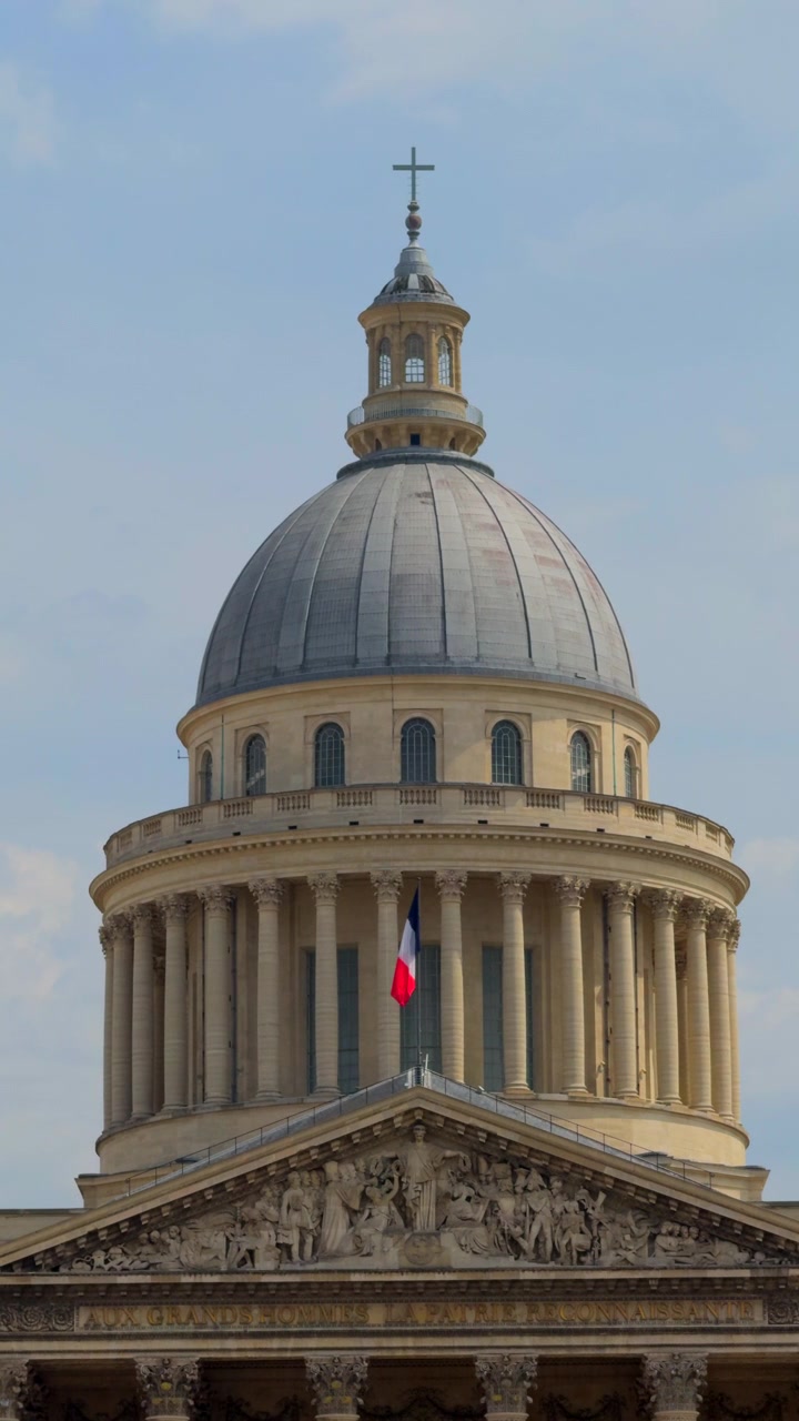 Cupola del Pantheon e architettura classica a Parigi con una bandiera francese che sventola al vento contro un cielo blu