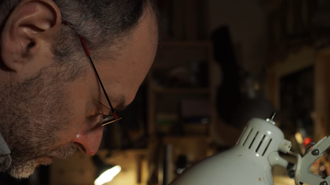 Master luthier, fully absorbed in his work, leans over his bench in a warmly lit Italian workshop, embodying skilled concentration and dedication