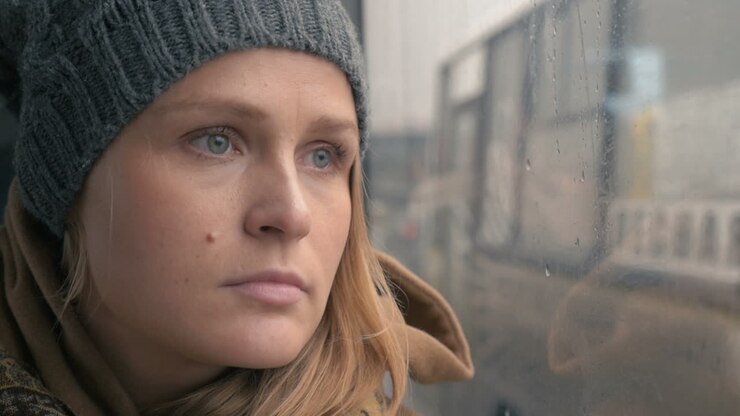 Woman staring through the wet bus window