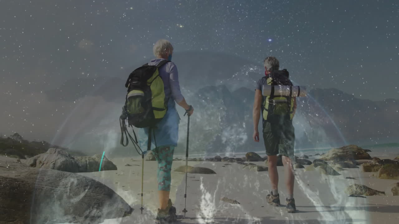 man and woman hiking starry beach at night with animated health icons using backpacks and poles