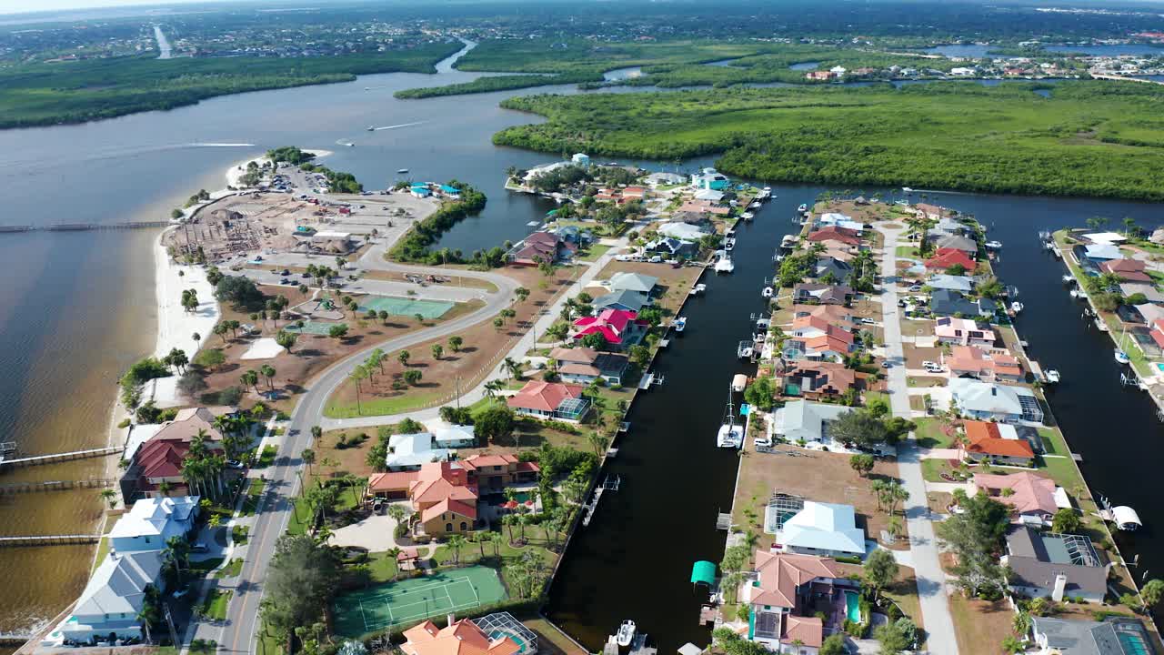 Asuinalue Port Charlottessa, Floridassa, esittää rantataloja, joissa on yksityiset laiturit, veneitä, hiekkaranta-alueita, vihreitä mangroveja ja mutkittelevia teitä aurinkoisessa rannikkomaisemassa