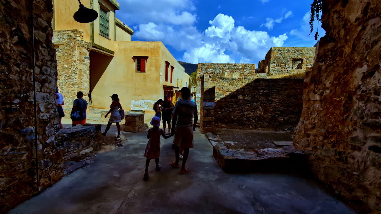 Tourists walking through the tunnel of an ancient rocky passageway of the ruins of the fortress of Spinalonga, Kalydon, in Elounda in northeastern Crete, in Lasithi, Elounda, Greece.