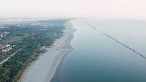 Luftaufnahme-Des-Sandstrandes-Mit-Sonnenschirmen,-Pavillons-Und-Der-Stadt