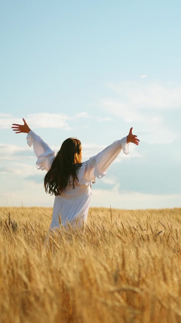 Mujer joven vestida de blanco caminando por un campo de trigo dorado