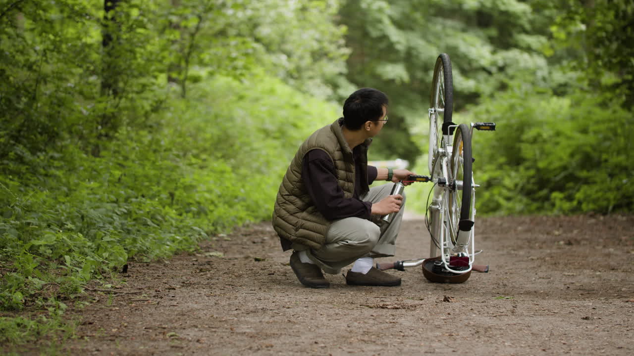 Man repairing a bicycle in a forest