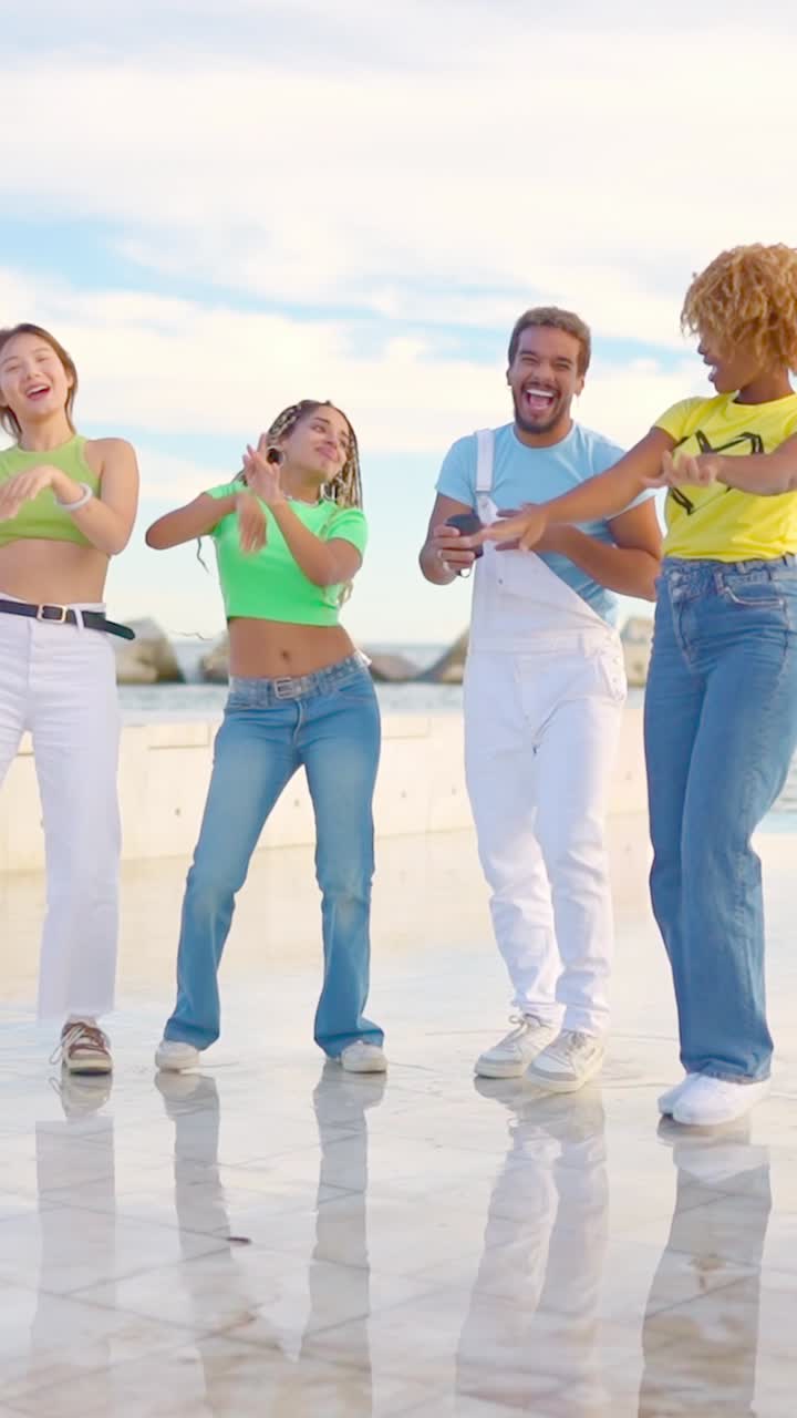 Multiracial friends dancing happily together next tot he sea