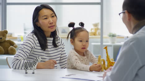 asian woman walking with kid in pediatrician office