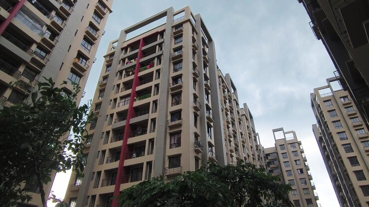 Vista dal basso di alti e moderni edifici residenziali sotto un cielo nuvoloso in India. Perfetto per contenuti immobiliari e di sviluppo urbano.
