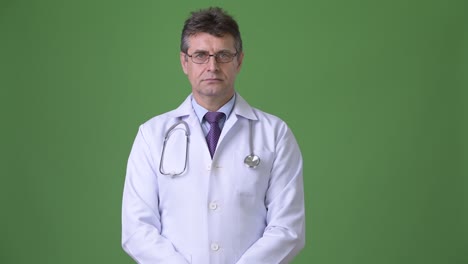 hombre maduro y guapo médico contra fondo verde