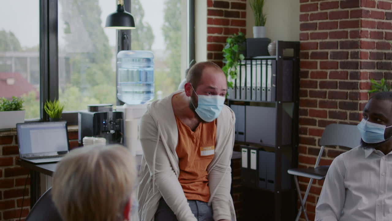 Angry man sharing mental health issues with group of people and counselor at aa meeting