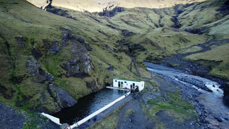 baño termal remoto en la zona rural de islandia, vasto paisaje montañoso volcánico, avión no tripulado