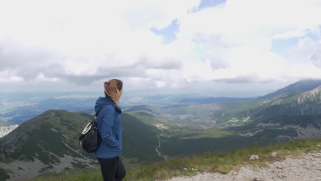 cinematic shot of a woman walking on top of a mountain in the tatra mountains admiring the landscape