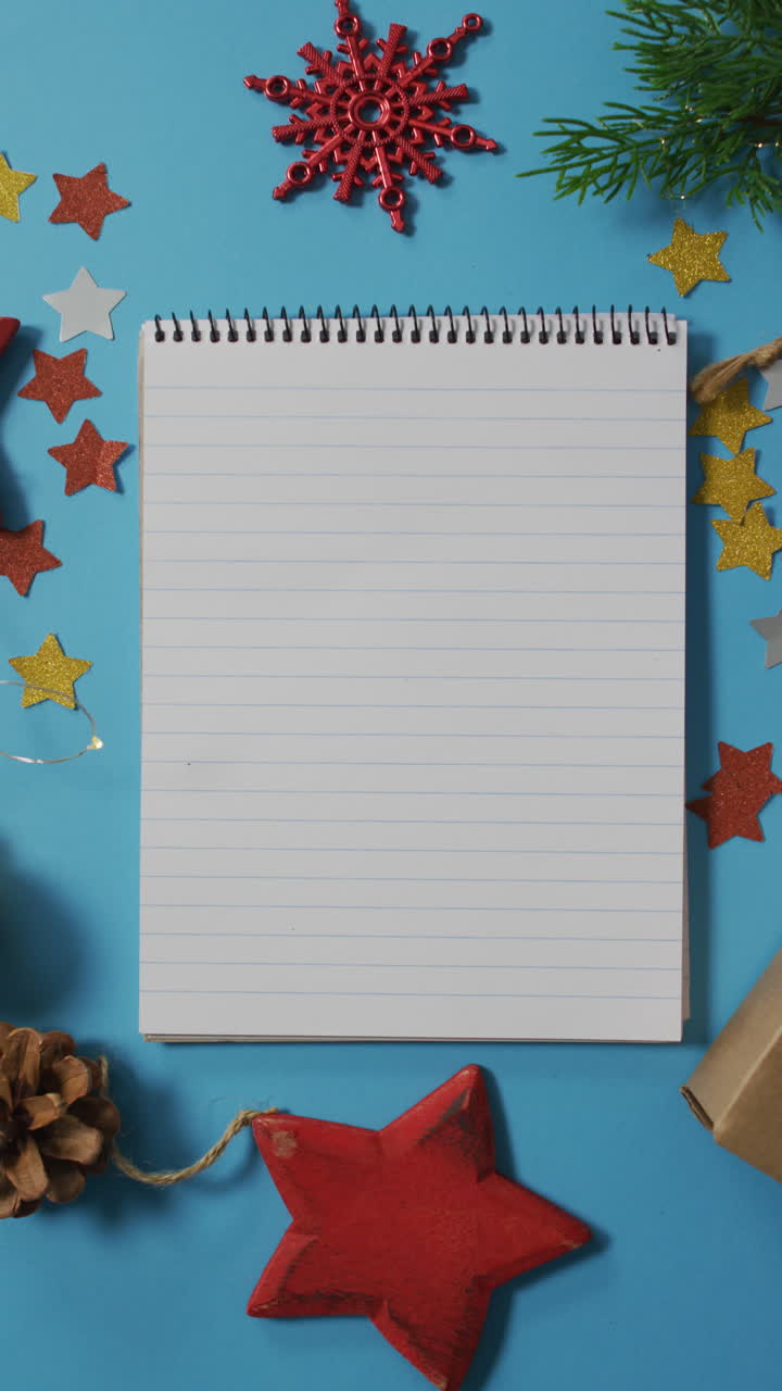 fotografía vertical de un cuaderno rodeado de decoraciones navideñas sobre un fondo azul