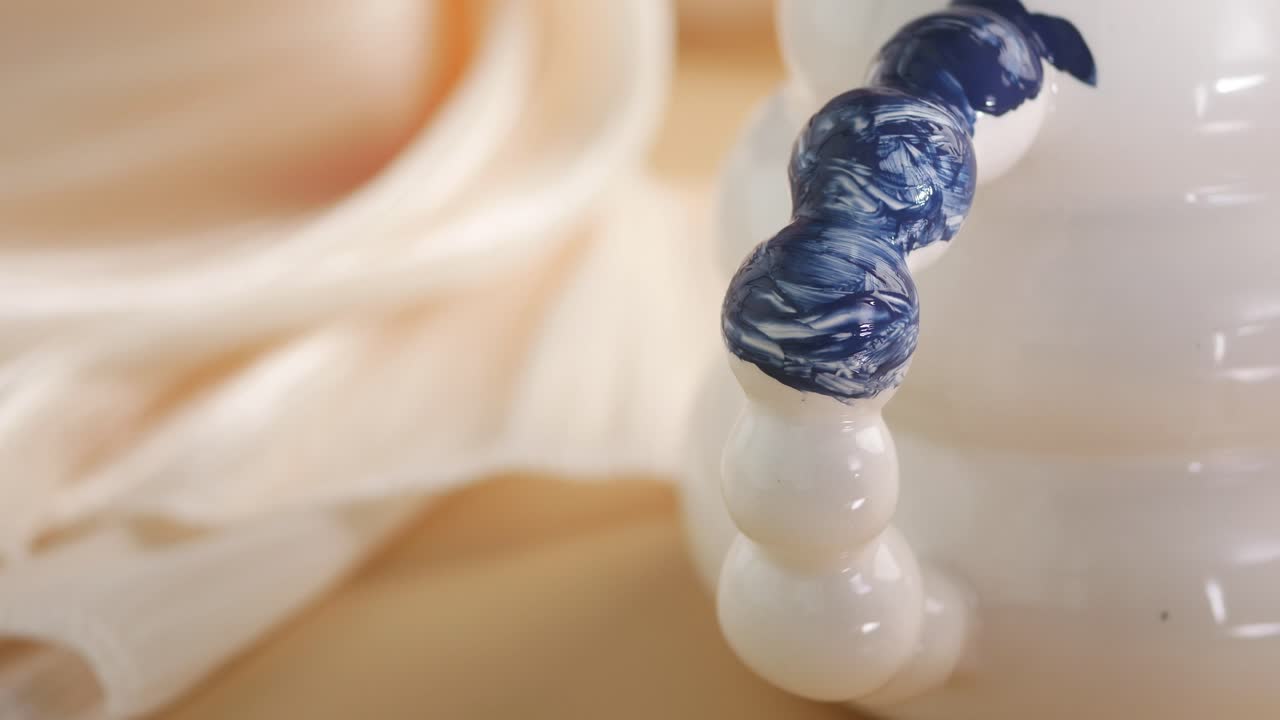 Close-up of a Paintbrush Applying Blue Paint to a White Sphere