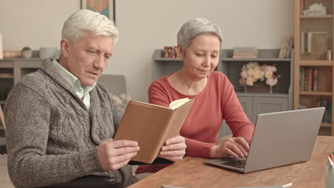 elderly couple learning with laptop and book