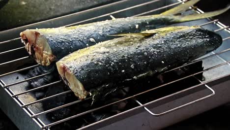 adding salt to a fish on a charcoal grill called inihaw or sinugba, an authentic traditional filipino dish in the philippines