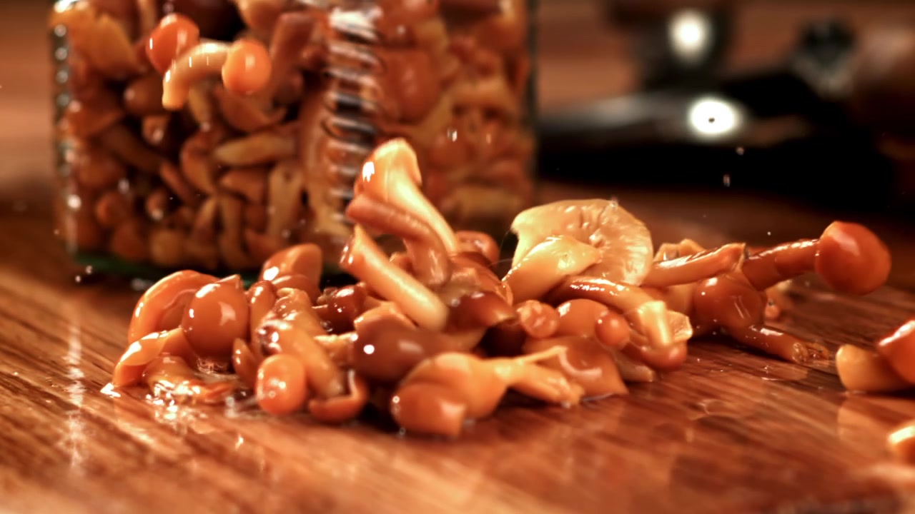 Pickled Mushrooms Falling onto a Wooden Table in Slow Motion