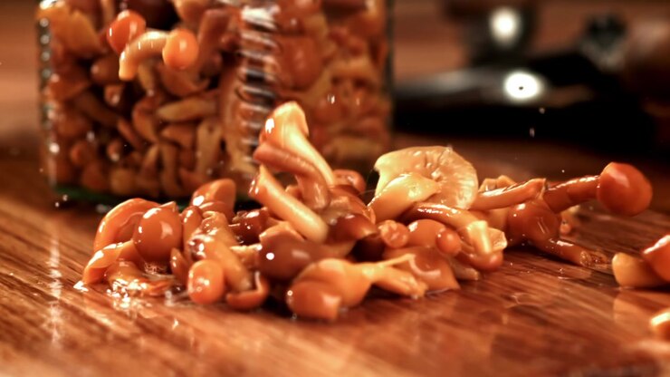Pickled Mushrooms Falling onto a Wooden Table in Slow Motion