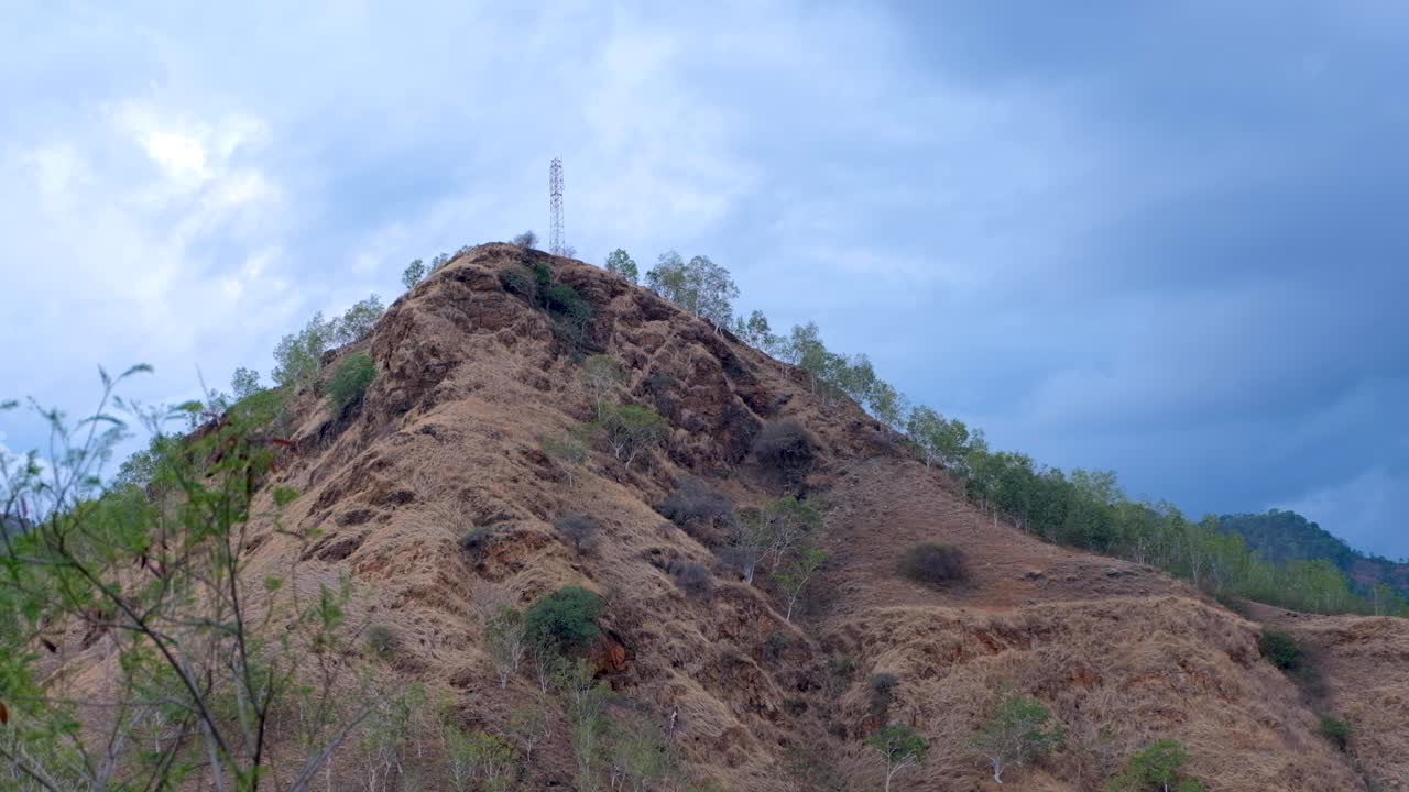 antena de torre de telecomunicaciones en la cima de una colina en el campo de un país en desarrollo con un cielo azul nublado como telón de fondo
