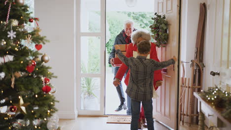 Excited-Grandson-Greeting-Grandparents-With-Presents-Visiting-On-Christmas-Day