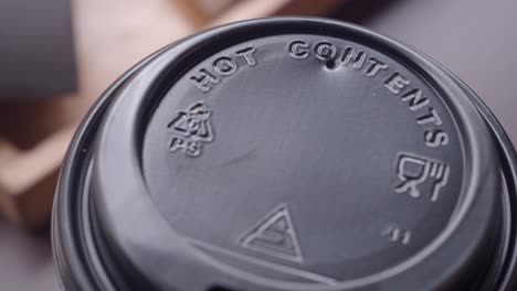 close-up of a disposable coffee cup lid with hot contents warning
