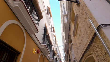 vista hacia arriba de un estrecho callejón con fachadas tradicionales en cádiz, españa