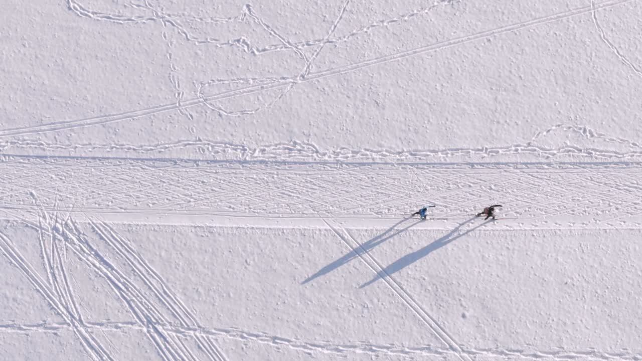 위에서 스킹 - 스노우 트랙에서 아름다운 겨울날 스키 커플을 내려다보는 드론의 탑 샷