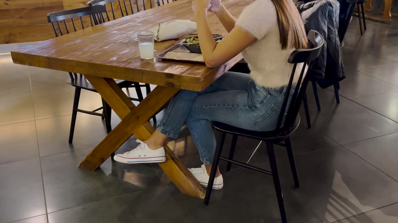 chica con ropa casual almorzando sola, mientras usa su teléfono celular