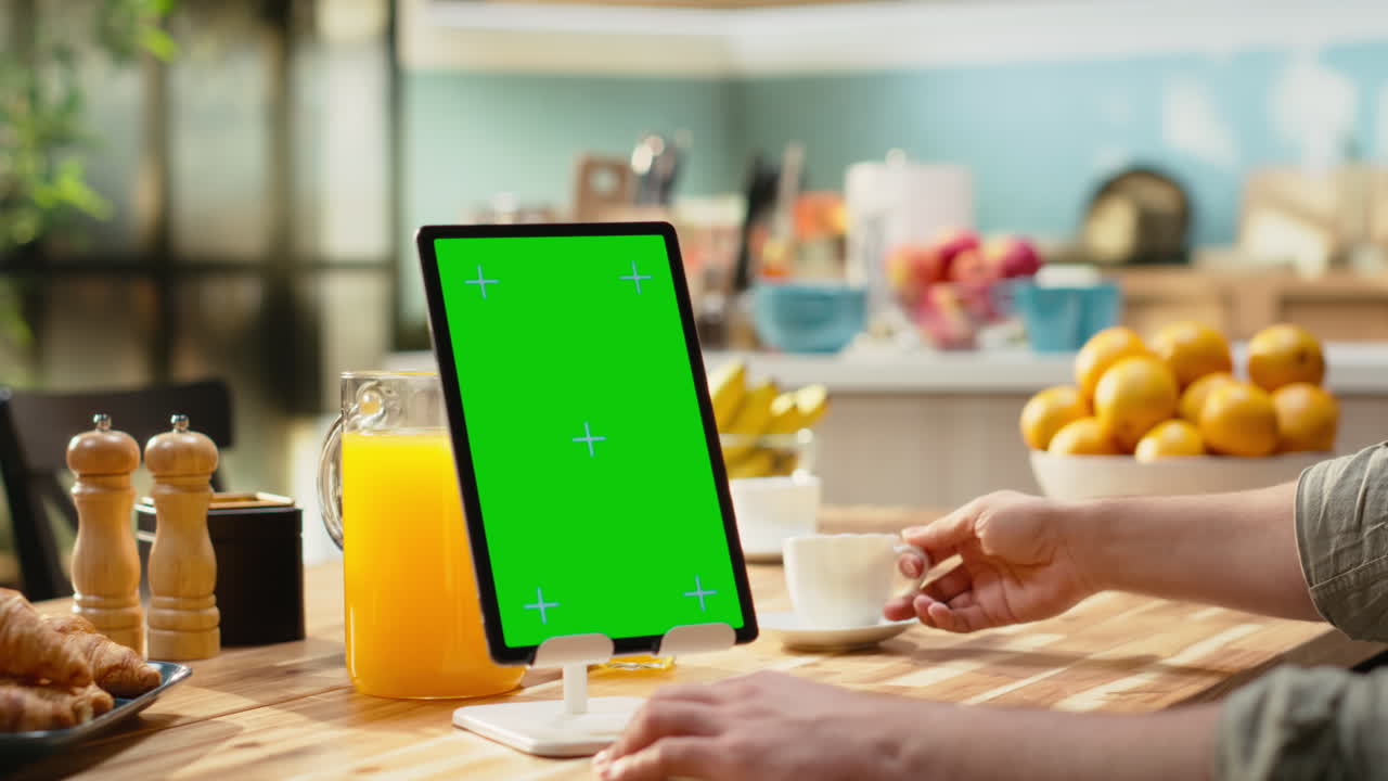 Layar hijau vertikal pada tablet dengan seorang pria duduk di meja kayu
