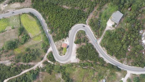 aerial descend over cars drive on serpentine mountain road in albania