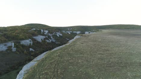 aerial view of a mountain valley with cliffs and forest