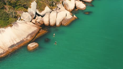 swimming in turquoise color water sea near big rocks