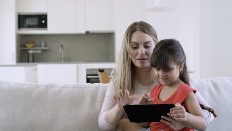 mom and cute little daughter using online app on tablet