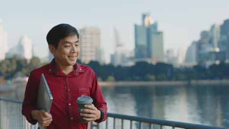 businessman walking in city park with laptop and coffee