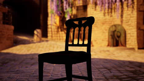 a black silhouette of a wooden chair sitting on a cobblestone street in front of a medieval village