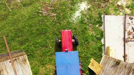 aerial top down view of red tractor driving out of barn and then backing up in
