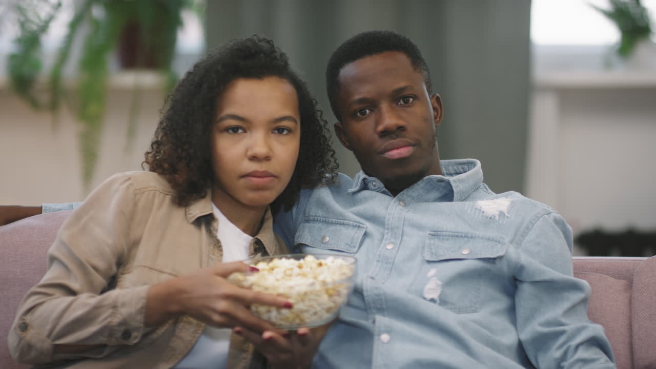 Coppia afro che guarda un film a casa in silenzio