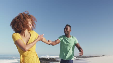 pareja afroamericana jugando en la playa