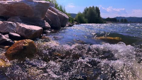 a serene riverbank scene capturing the gentle flow of water and surrounding nature under bright blue skies with scenic rock formations and lush greenery