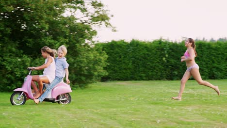 pre-teen kids having fun in garden with scooter and dog