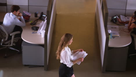 young woman walking with paperwork in office, elevated view