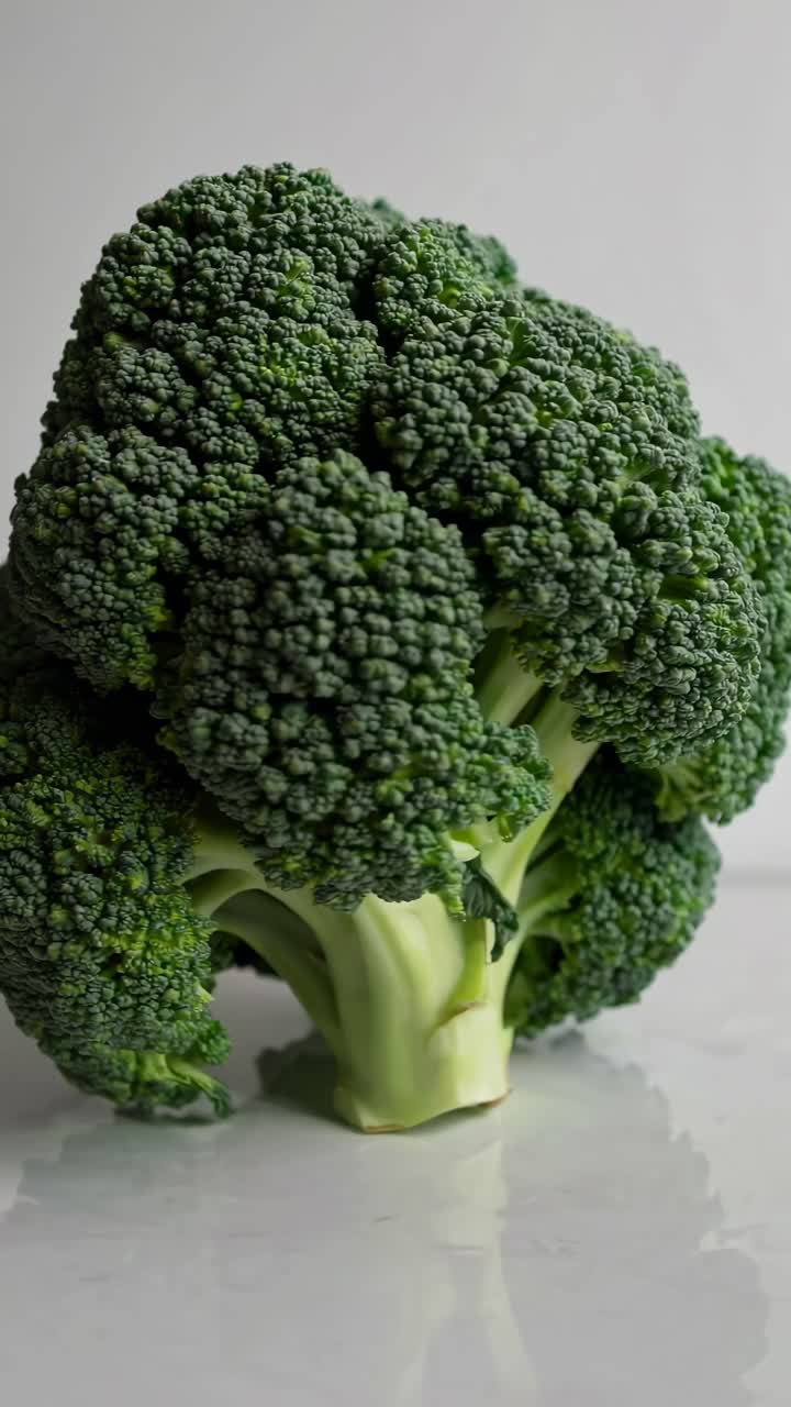 Video ravvicinato di broccoli freschi su una superficie riflettente, che evidenzia consistenza e vivacità