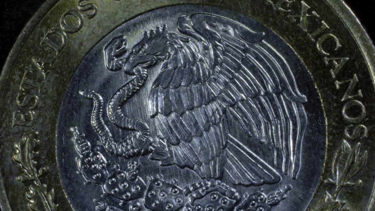 Close up of a Mexican ten-peso coin with a smooth zoom out revealing metallic texture under soft light