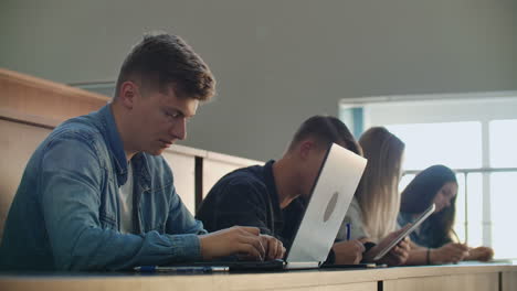 Eine-Große-Gruppe-Multiethnischer-Studenten-Arbeitet-An-Ihren-Laptops,-Während-Sie-Im-Modernen-Klassenzimmer-Einer-Vorlesung-Lauschen.-Kluge-Junge-Leute-Studieren-An-Der-Universität.