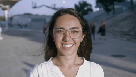 attractive young brunette woman smiling widely wearing white blouse and glasses