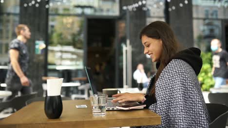 mujer trabajando en una computadora portátil en un café al aire libre