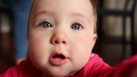 Cute-little-baby-smiles-and-grabs-the-camera,-close-up-shot-in-slow-motion