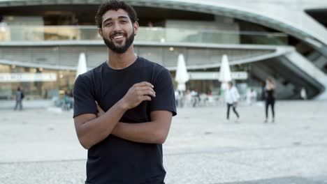 smiling curly guy with crossed arms standing on street