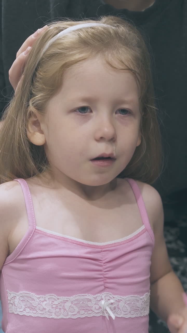 careful mommy irrigates nose of scared little girl with nasal spray at large mirror in bathroom at home