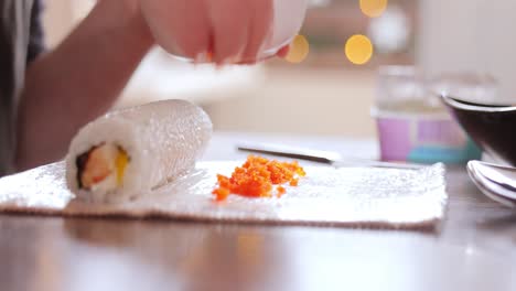 hacer sushi en la cocina de casa. manos de mujer enrollando sushi casero.